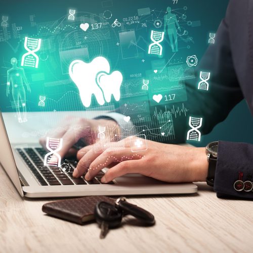 hand browsing on the internet for medical issues with dental icons coming out from the screen